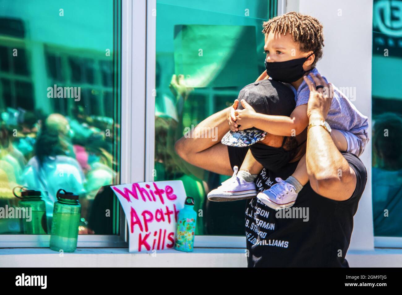 05-30-2020 Tulsa USA Aadorables paseos de niños negros de sus padres hombros agarrando su cabeza, ambos usando máscaras, con reflejos de BLM protesta blu Foto de stock