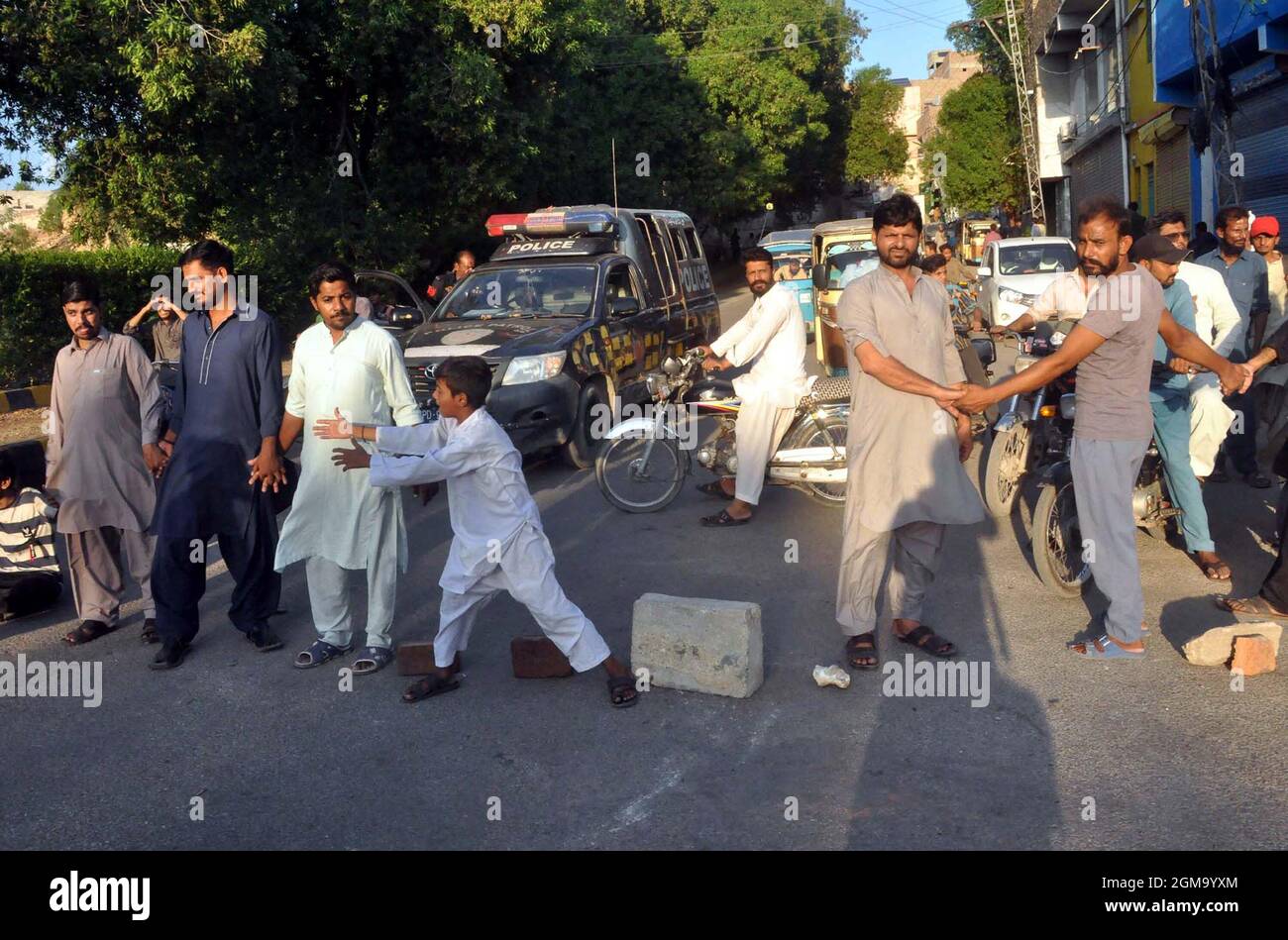 Los residentes de la colonia Shah Faisal son carreteras de bloque ya que están realizando una manifestación de protesta contra la prolongación del desprendimiento de carga eléctrica en su área, en la carretera Hill Top en Hyderabad el viernes 17 de septiembre de 2021. Foto de stock