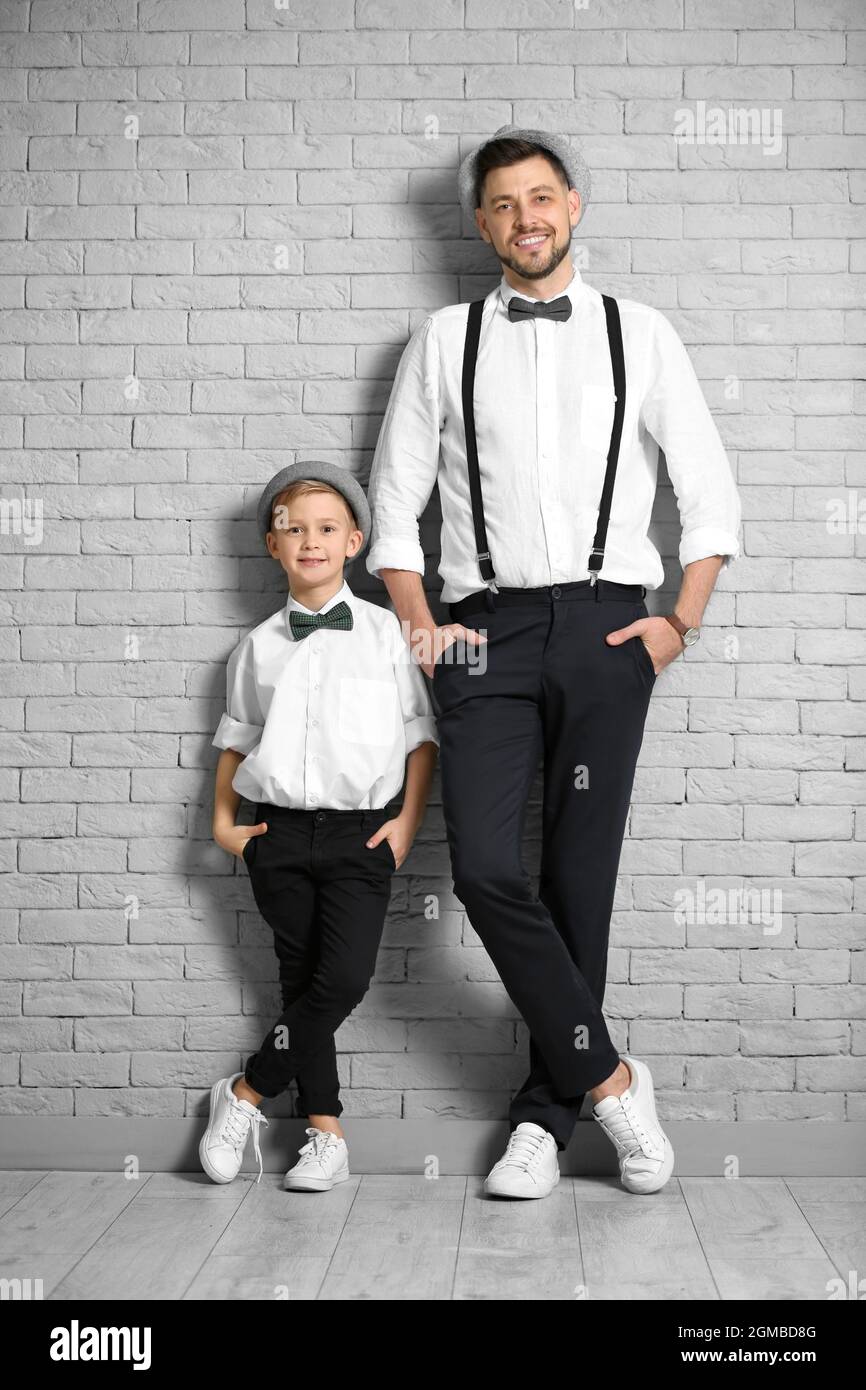 Padre e hijo en elegantes trajes contra la pared de ladrillo Fotografía de  stock - Alamy
