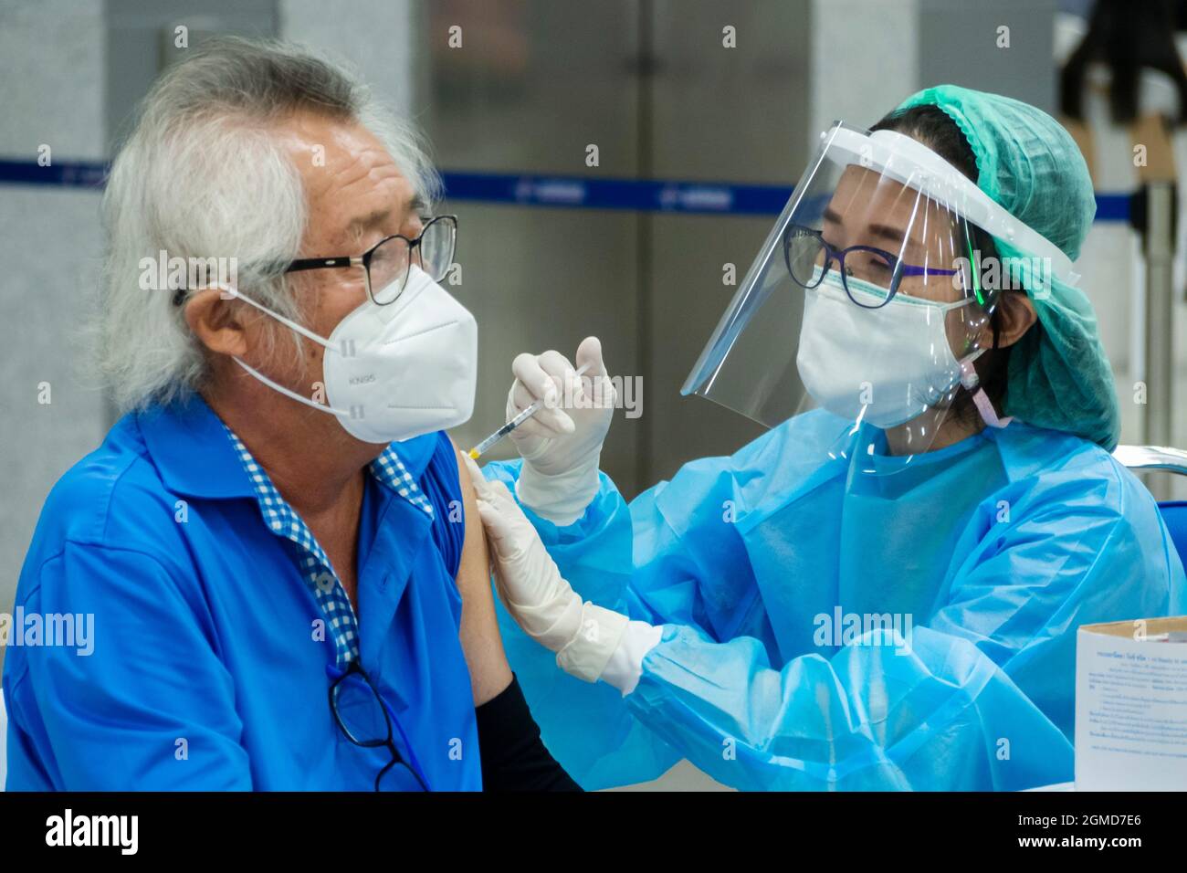 Bangkok, Tailandia - 17 de septiembre de 2021 : Médico o enfermera asiática que administra vacuna antivirus covid a un paciente anciano que usa máscara facial protectora Foto de stock