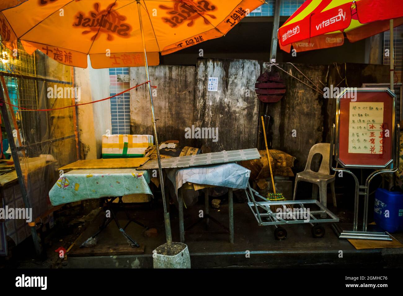 Escena callejera fuera de un restaurante: Mesas de repuesto, sombrillas y un cartel, en Tai O, Isla Lantau, Hong Kong Foto de stock