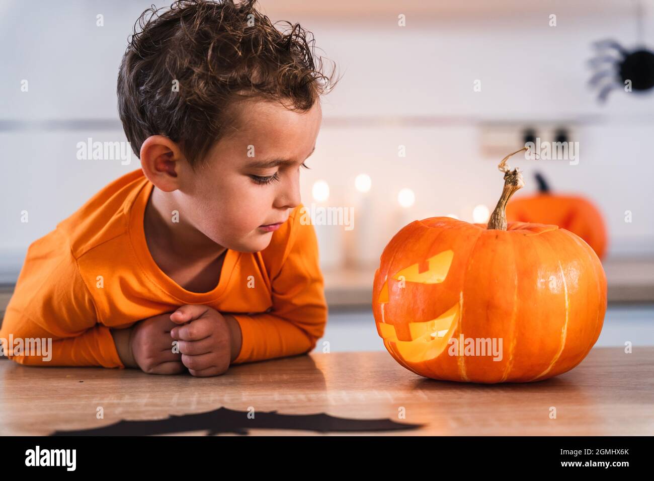 Retrato de un niño mirando su calabaza decorada e iluminada para las vacaciones de halloween en casa Foto de stock