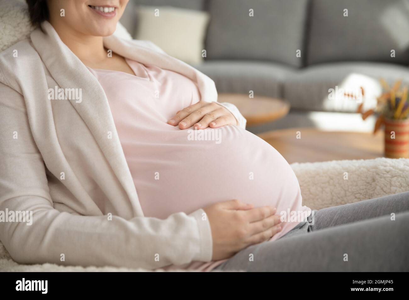 Sonriendo joven futura mamá mujer sosteniendo las manos en el vientre embarazada Foto de stock