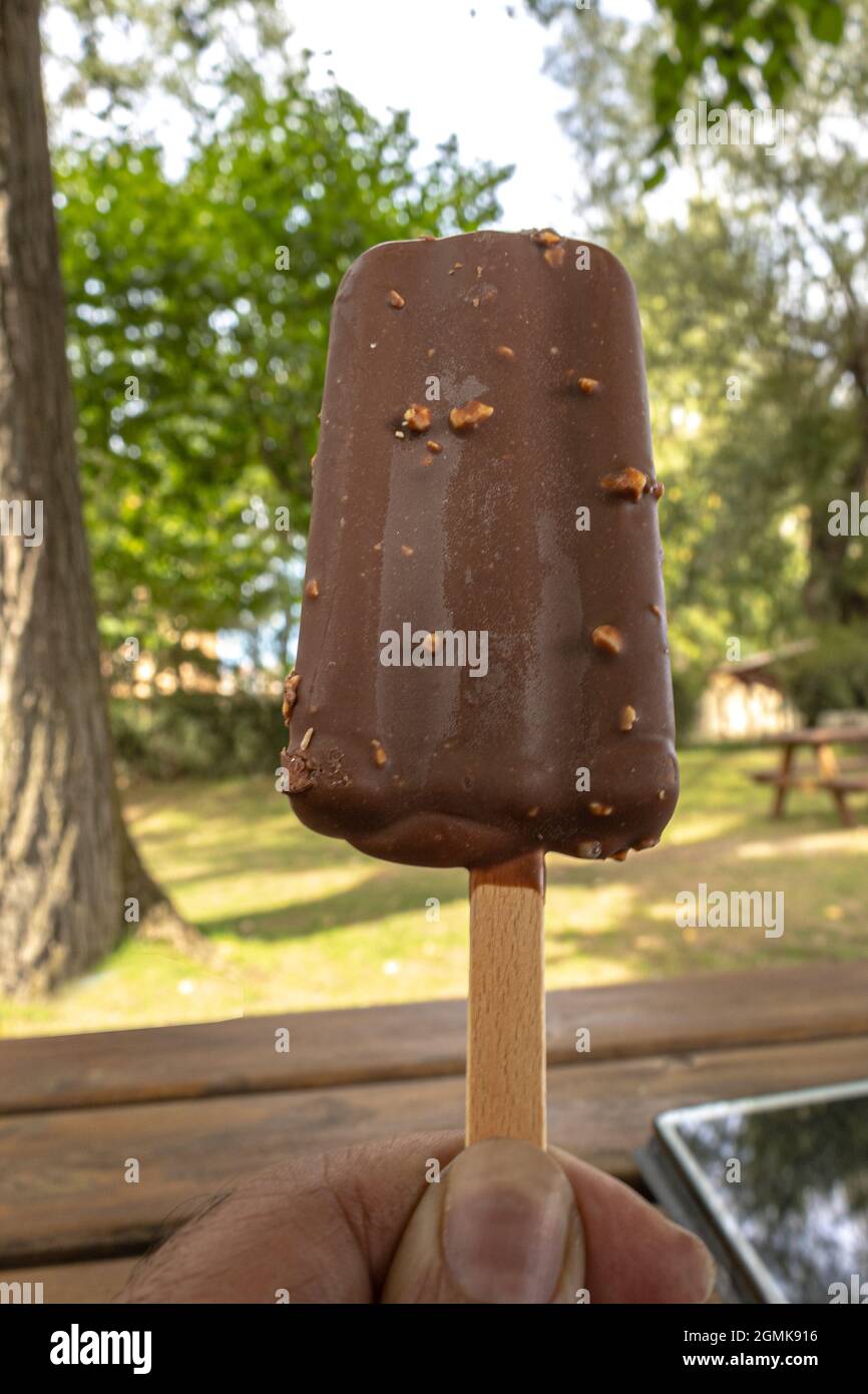 helado de chocolate con almendras sostenido en una mano como un descanso  del teletrabajo en una mesa de jardín Fotografía de stock - Alamy
