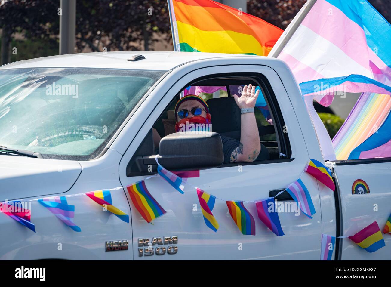 ROSEVILLE, CA, EE.UU. - SEPTIEMBRE. 19, 2021: Atom Vaughn, un hombre trans, ondea en la barba arcoiris mientras conduce su camión decorado con arco iris y bandera trans. Foto de stock