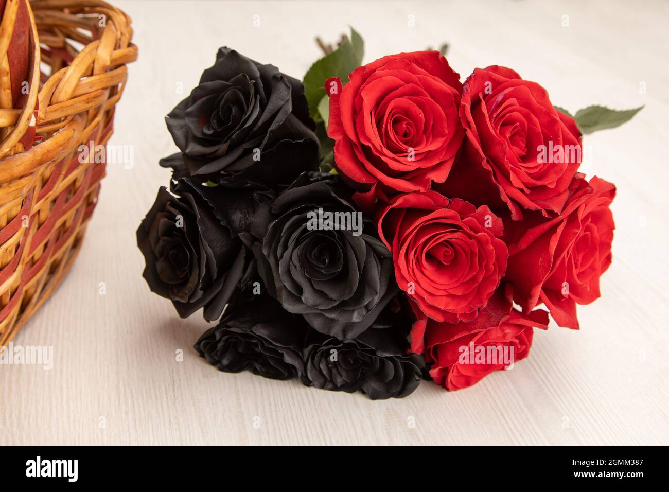 detalles de un ramo con flores de rosas negras y rojas, junto a una cesta  de mimbre, hermosa decoración con belleza de la naturaleza en una mesa,  detalle de la pe Fotografía