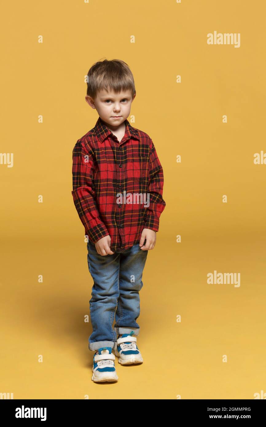 Retrato chico serio en camisa a cuadros y jeans Foto de stock
