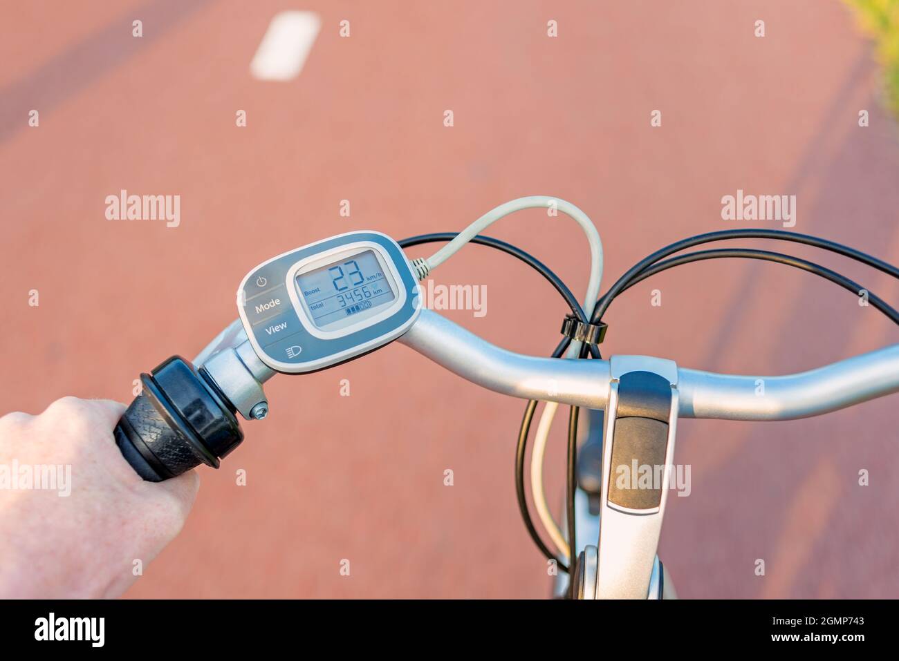 Perspectiva en primera persona en el panel de control del manillar de la bicicleta eléctrica mientras conduce por el carril de la bicicleta Foto de stock
