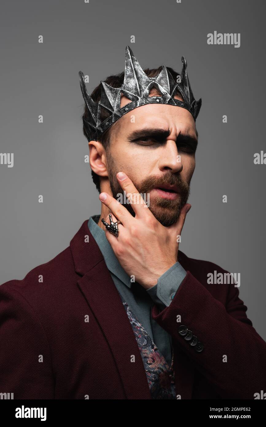 hombre pensativo en vampiro rey halloween corona tocando la barbilla  mientras mira la cámara aislada en gris Fotografía de stock - Alamy