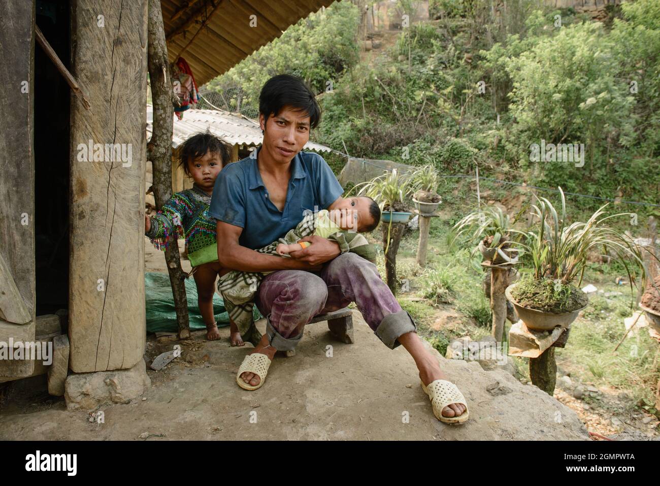 Sapa, Vietnam - 14 de abril de 2016: Padre vietnamita con hijos en casa mientras su esposa está trabajando. Paternidad en Asia, zona rural pobre. Foto de stock