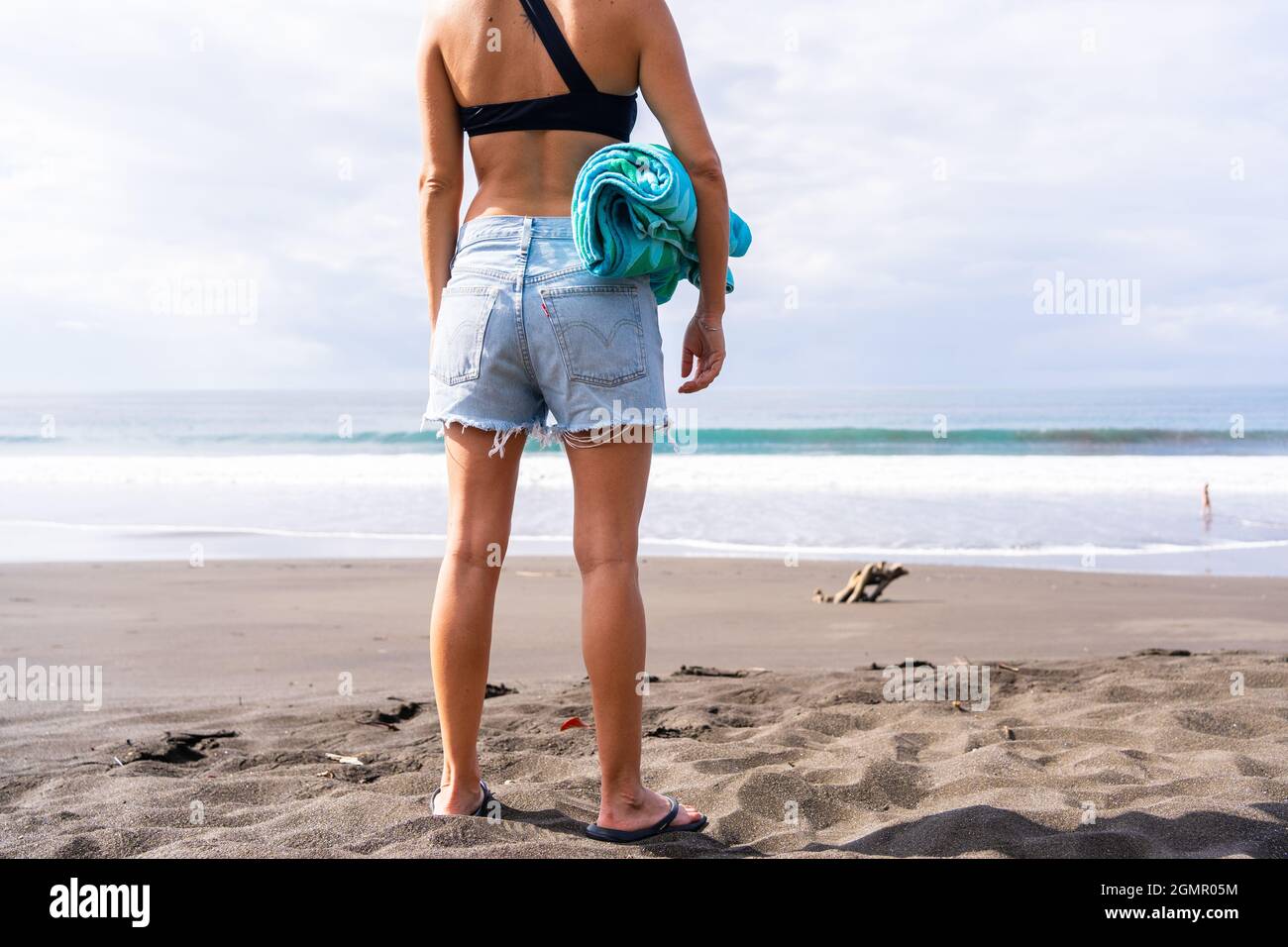 Parte posterior del cuerpo de una mujer en un bikini y pantalones cortos de  pie en una playa desierta sosteniendo una toalla. Playa Jaco en Costa Rica  Fotografía de stock - Alamy