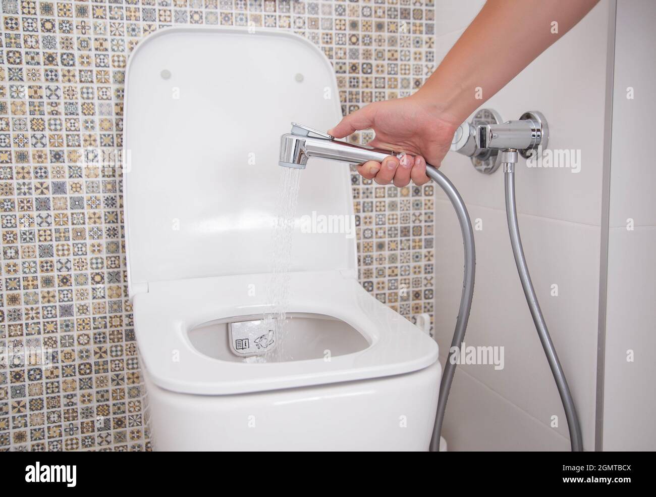 Un hombre sostiene una ducha higiénica contra el fondo del váter. Concepto  de higiene y cuidado corporal íntimo Fotografía de stock - Alamy