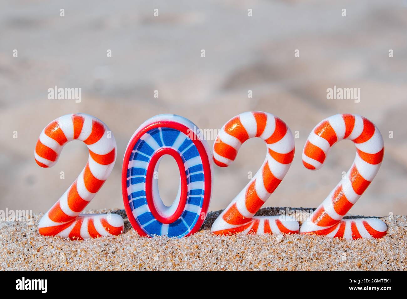 Los números divertidos brillantes de Año Nuevo 2022 en rayas, en la playa de arena junto al mar, selective focus.Tourism, recreación y viaje concept.Creative tarjeta de Año Nuevo Foto de stock