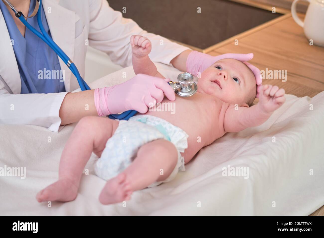 El médico corta las uñas de los pies de un bebé recién nacido. Una  enfermera uniforme con tijeras para la higiene de las piernas y pies del  niño Fotografía de stock 