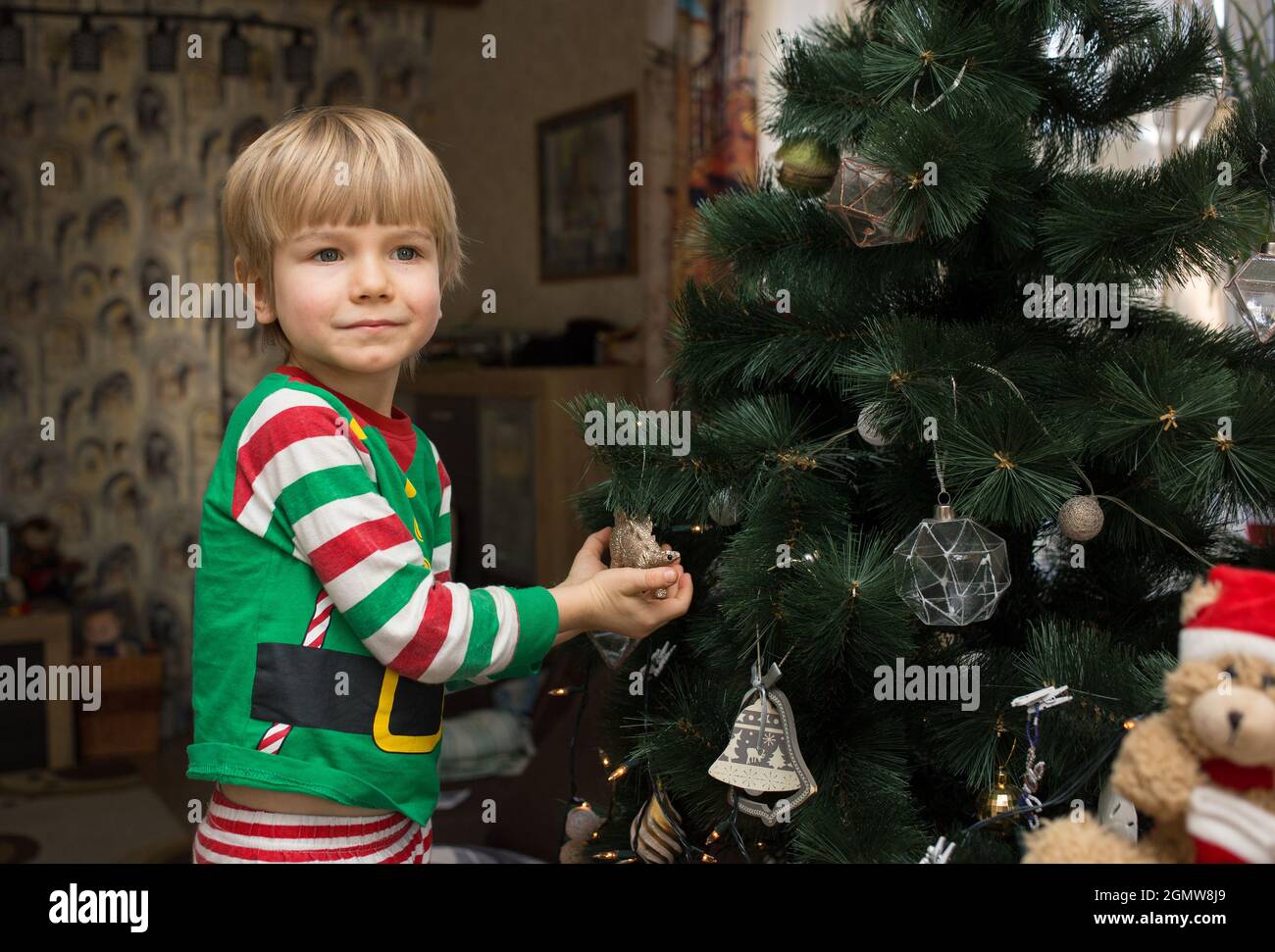 Lindo niño vestido con pijama de elfo decora el árbol de Navidad. Esperando  un milagro, preparándose para la Navidad. Los sueños de los niños, la  infancia Fotografía de stock - Alamy