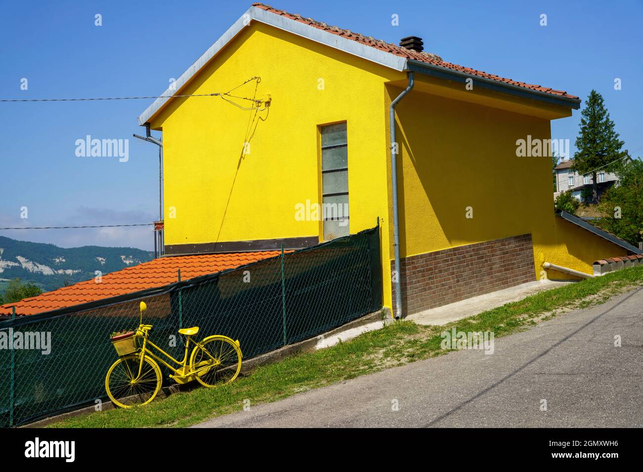 Casa amarilla y bicicleta a lo largo de la carretera de Garpagna a Brignano, provincia de Alessandria, Piamonte, Italia Foto de stock