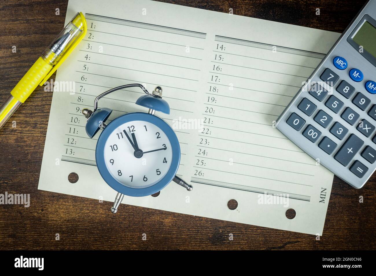 Organizador de oficina con una calculadora y un reloj despertador  configurado para cinco a doce, el concepto de resúmenes y una programación  de tareas bajo presión de tiempo Fotografía de stock -