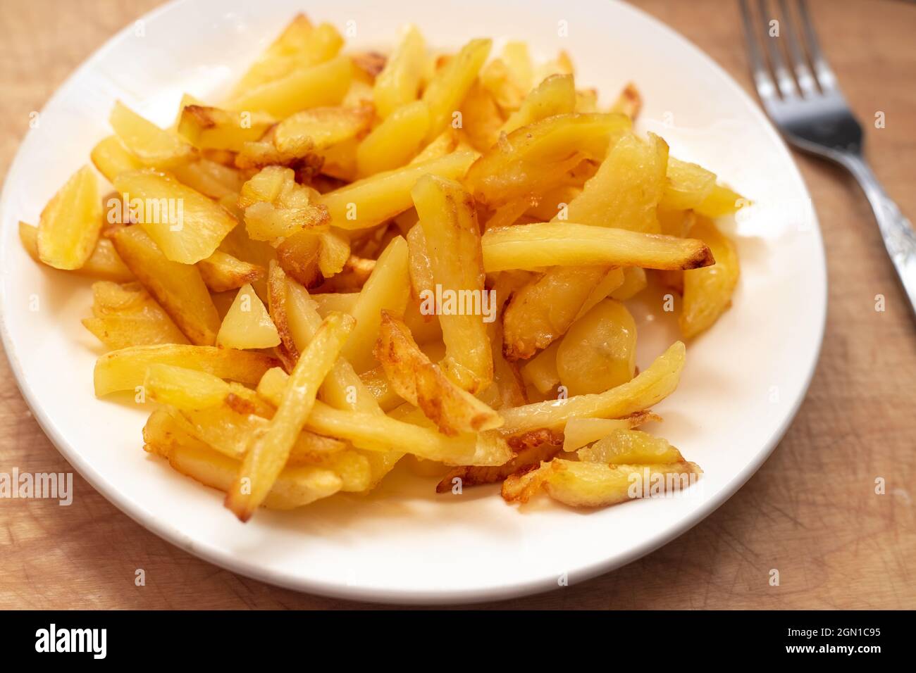Patatas fritas doradas frescas en un plato blanco. Delicioso plato de verduras. Foto de stock