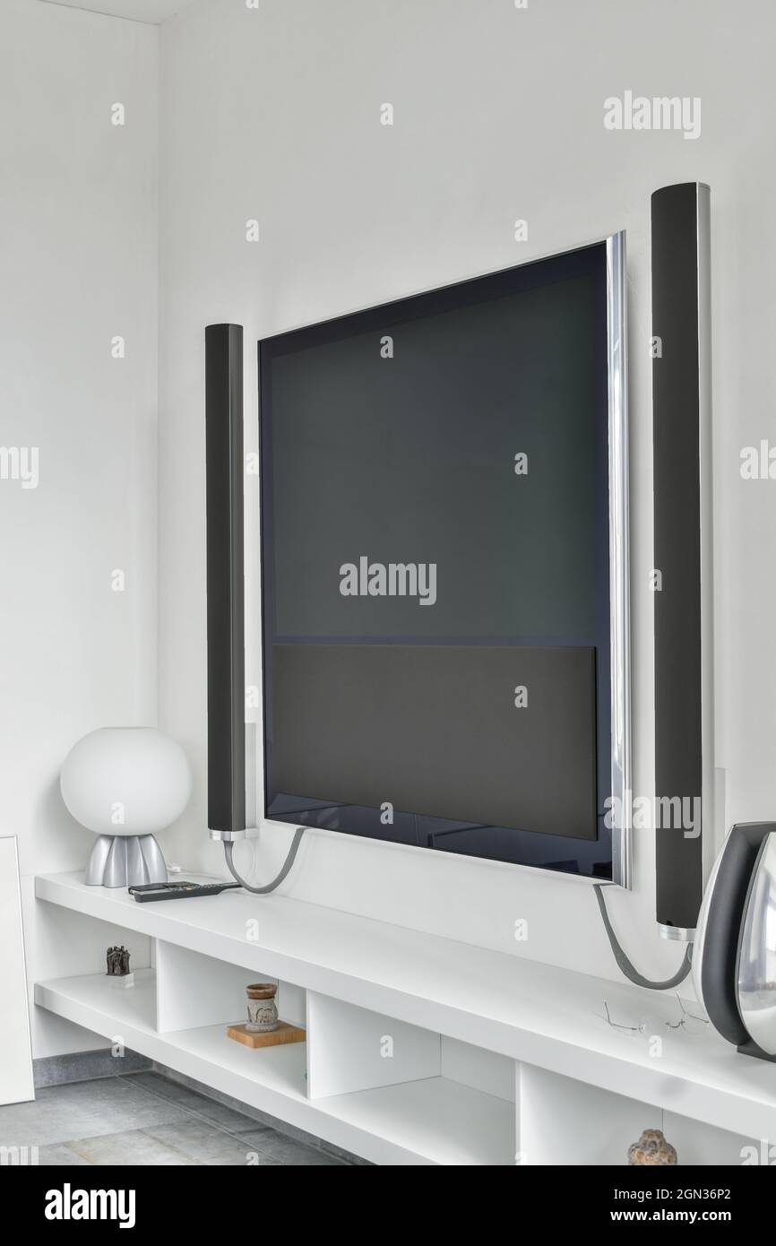 Moderno televisor con altavoces acústicos colgados en la pared debajo de  los estantes en un apartamento minimalista Fotografía de stock - Alamy