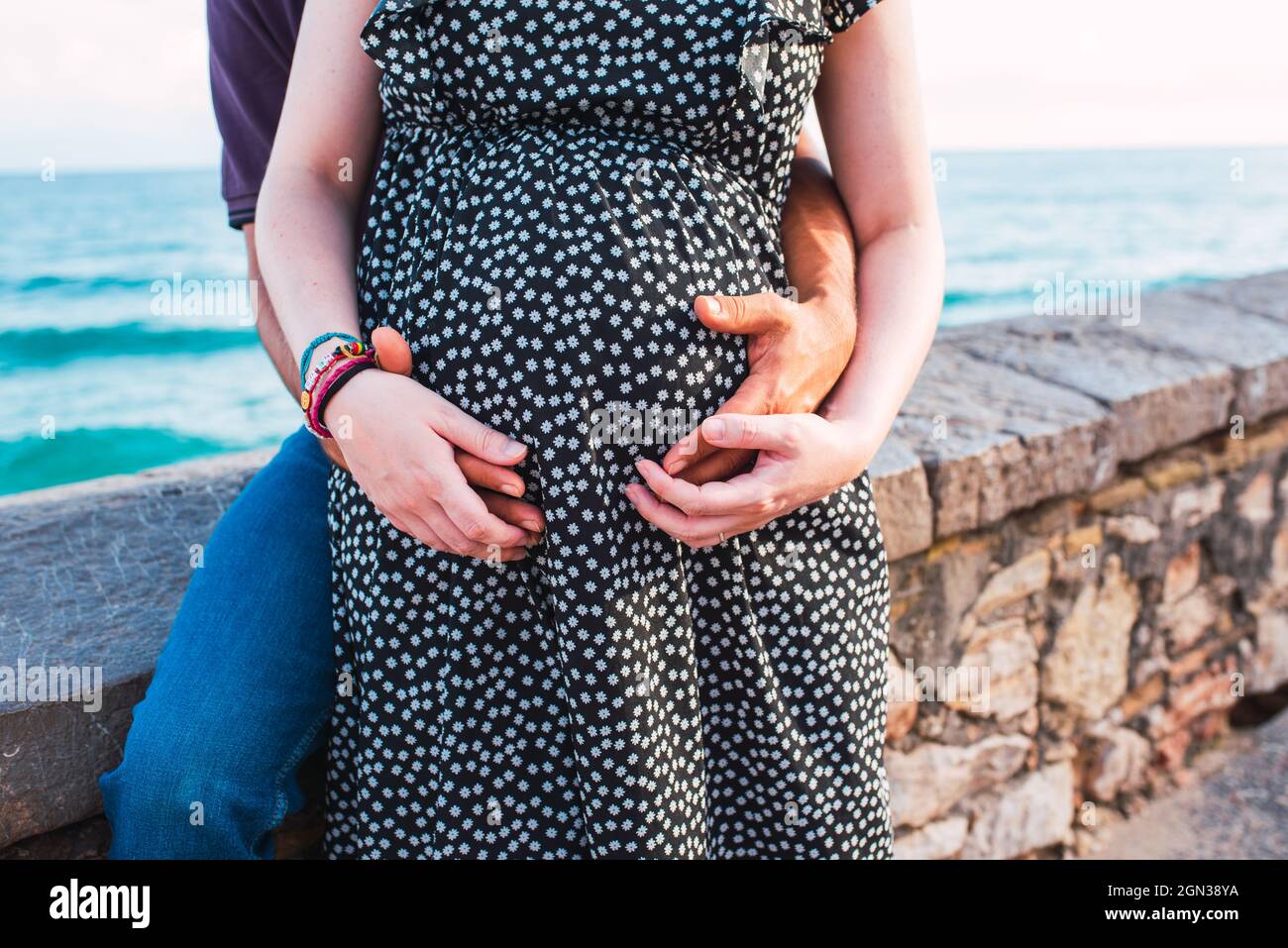Pareja interracial esperando un bebé. Las manos se agarraron en el vientre de la mujer embarazada. Foto de stock