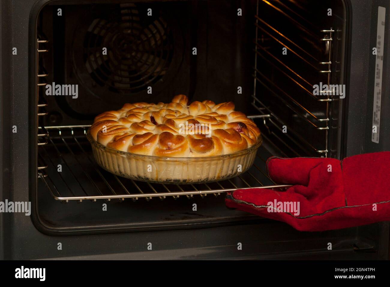 El pastel acabado con relleno de fruta se retira del horno. Un panadero con  guantes resistentes al calor saca una torta acabada de un horno eléctrico  Fotografía de stock - Alamy