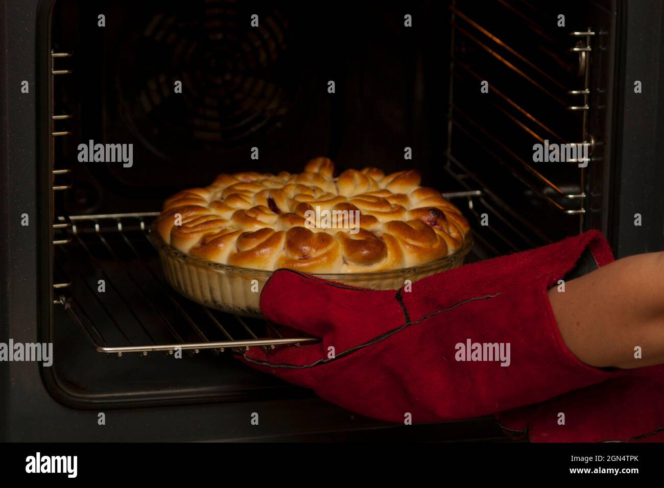 El pastel acabado con relleno de fruta se retira del horno. Un panadero con  guantes resistentes al calor saca una torta acabada de un horno eléctrico  Fotografía de stock - Alamy