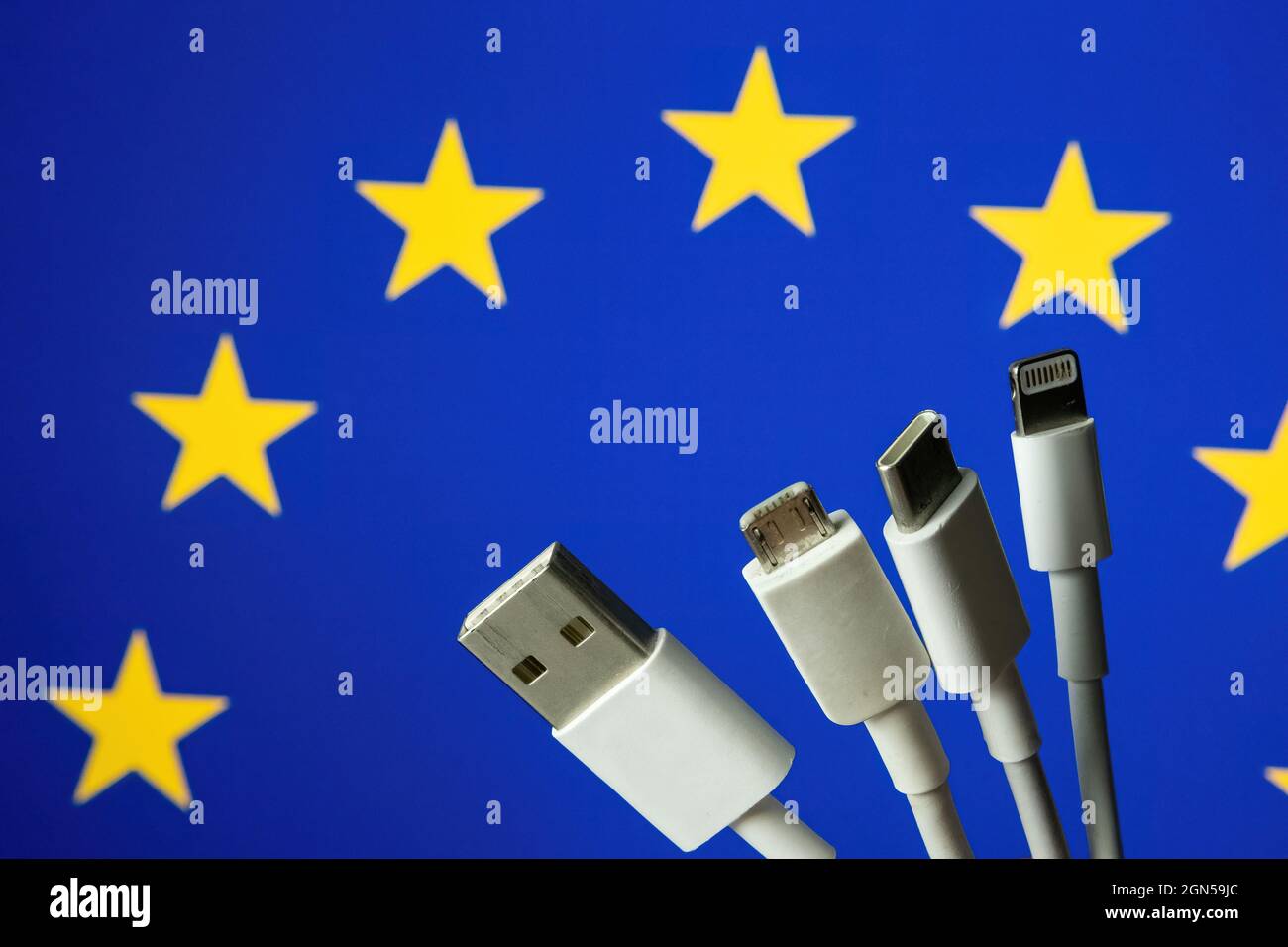 Bandera de la UE y diferentes cables de carga como USB, USB-C, Micro USB, cable Lightning. Concepto para la nueva legislación sobre cables de carga universal de la UE. Foto de stock
