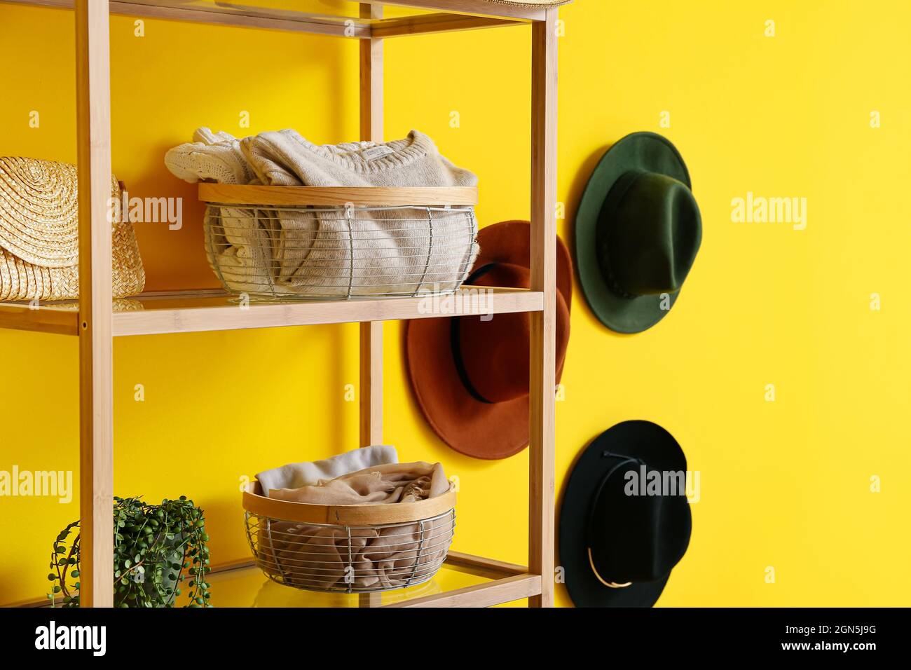 Organizadores modernos con ropa en estante cerca de la pared amarilla  Fotografía de stock - Alamy