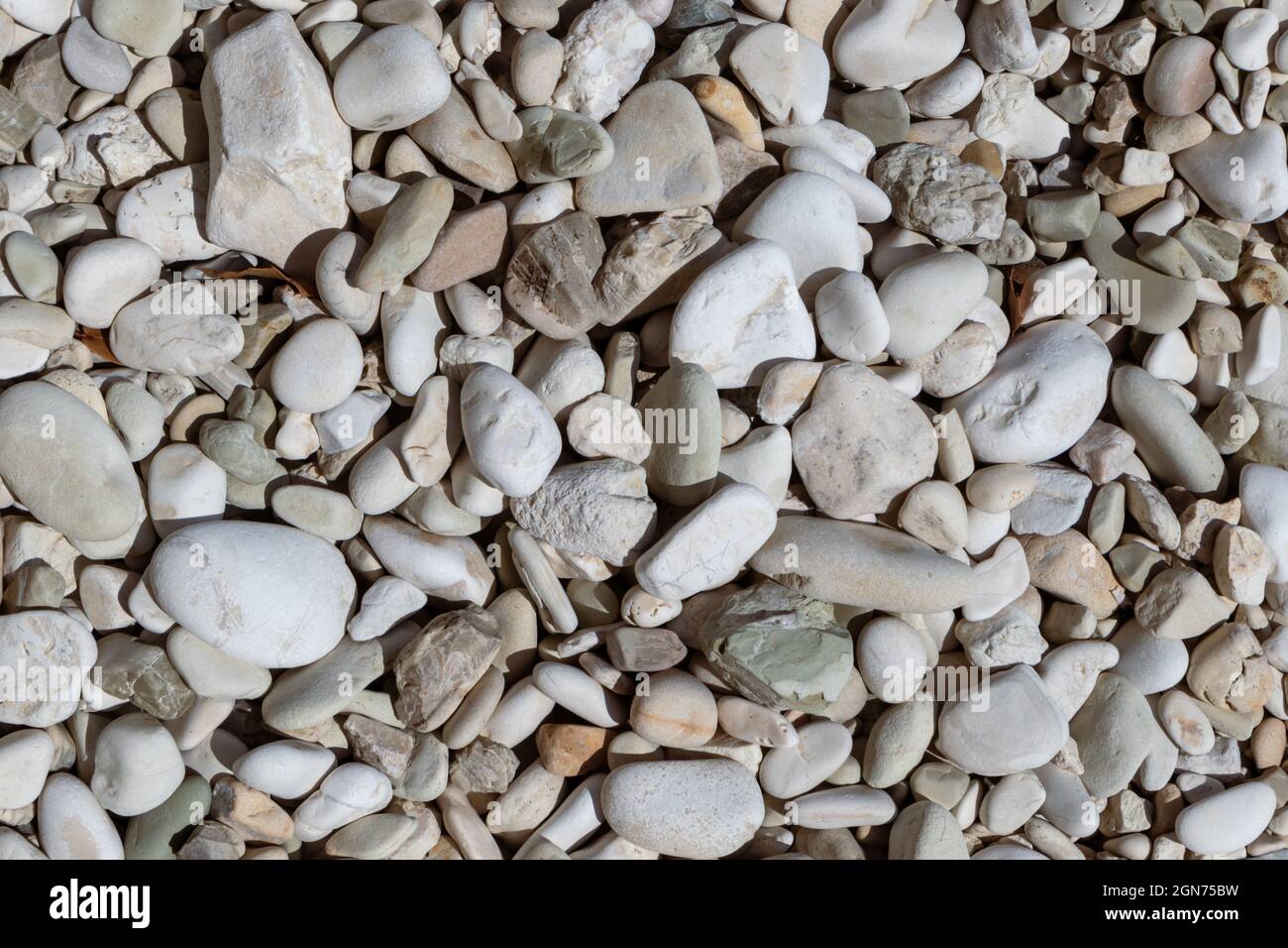 Mar Jónico costa guijónica piedra mármol playa de primer plano textura. Rocas de colores blanco y beige en la isla de Lefkada, Grecia Foto de stock