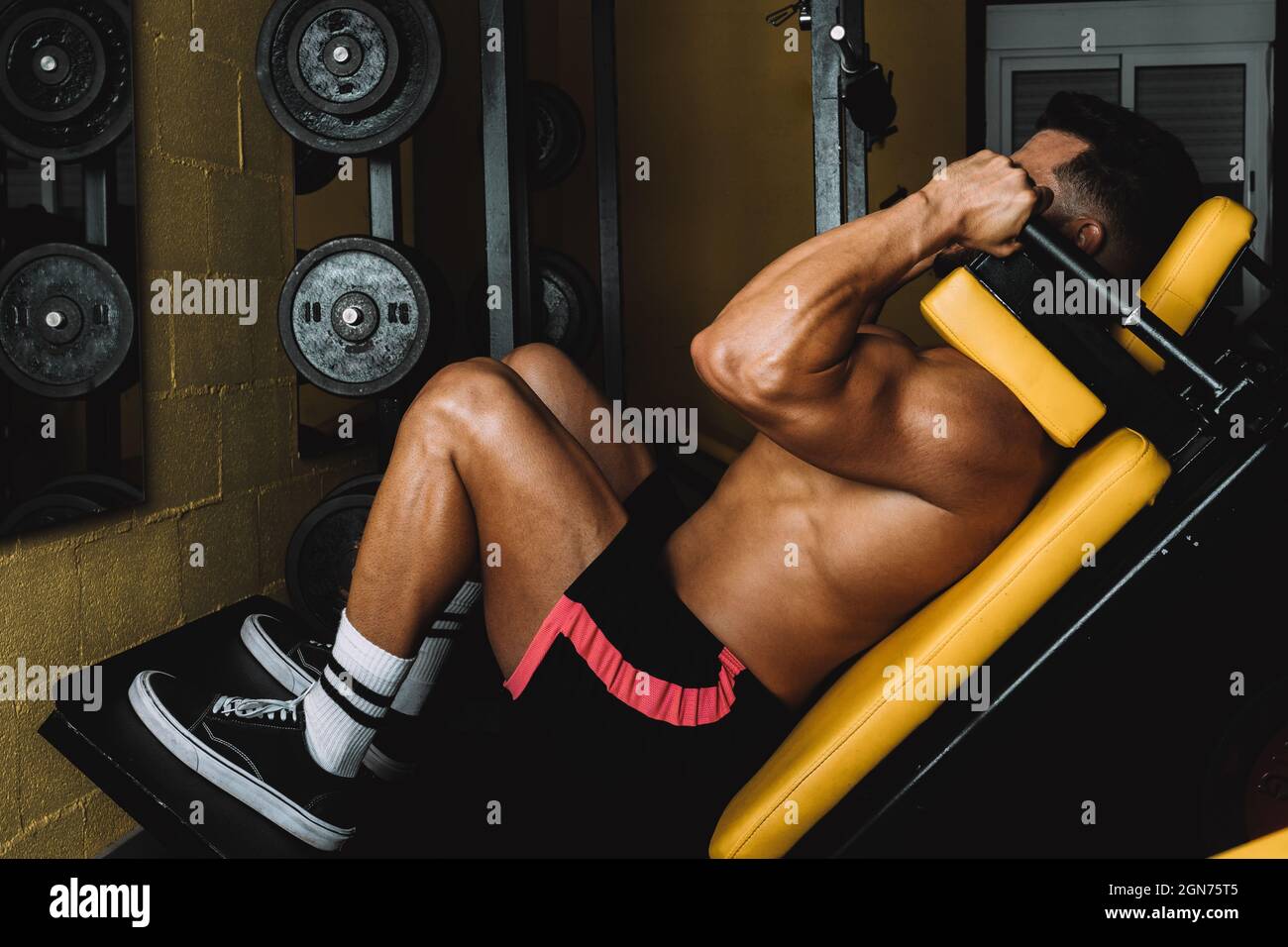 Hombre en ropa deportiva construyendo sus piernas con una máquina de  gimnasio Fotografía de stock - Alamy