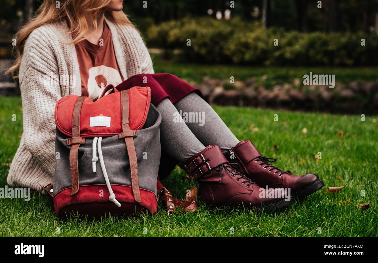 Chica con chaqueta de punto, falda de borgoña y zapatos de cuero está  acostada boca abajo sobre hierba verde en un parque de la ciudad. Cansado  de la escuela Fotografía de stock - Alamy
