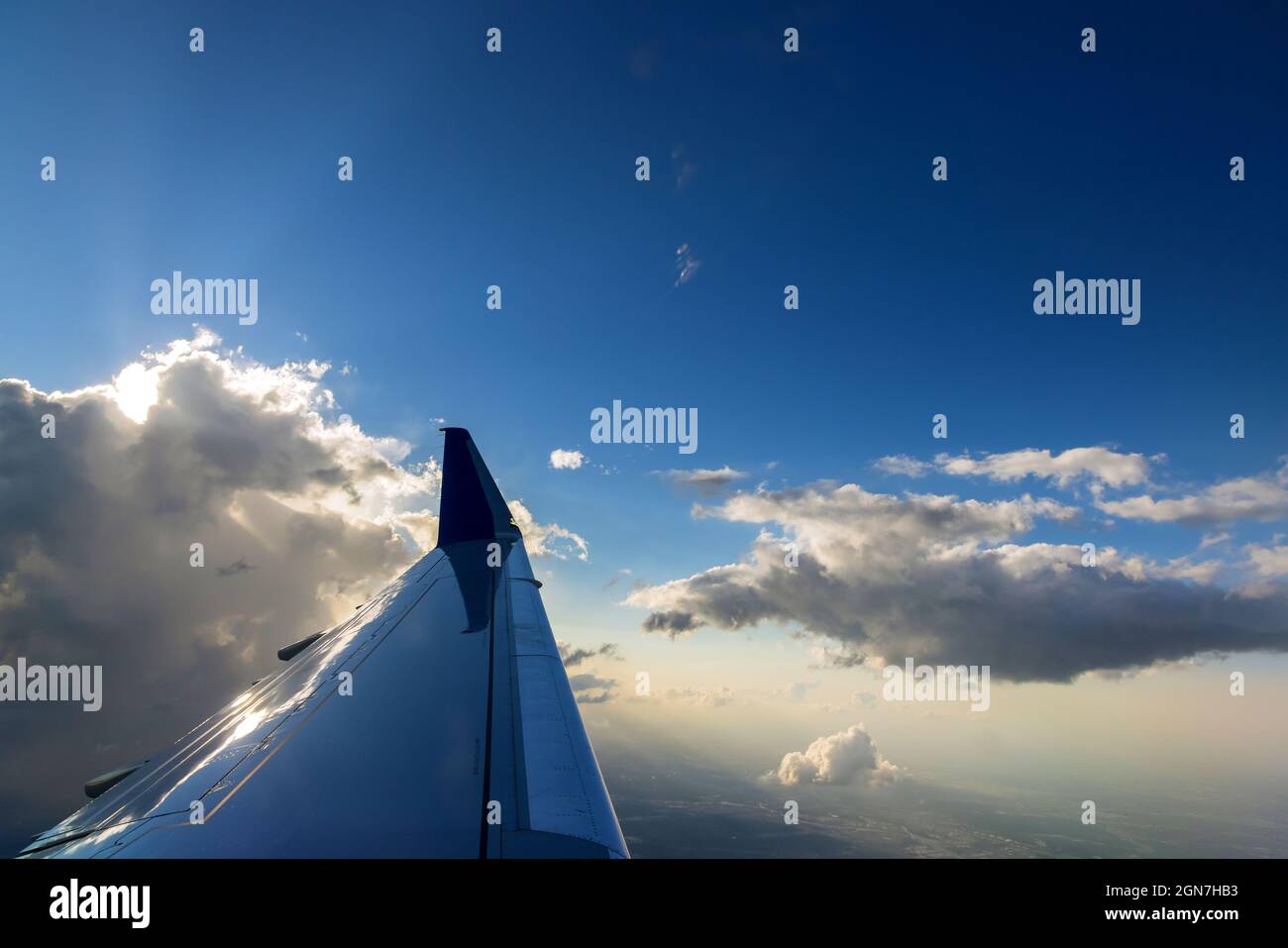 Vista del ala del avión durante una hermosa y colorida puesta de sol nublada Foto de stock