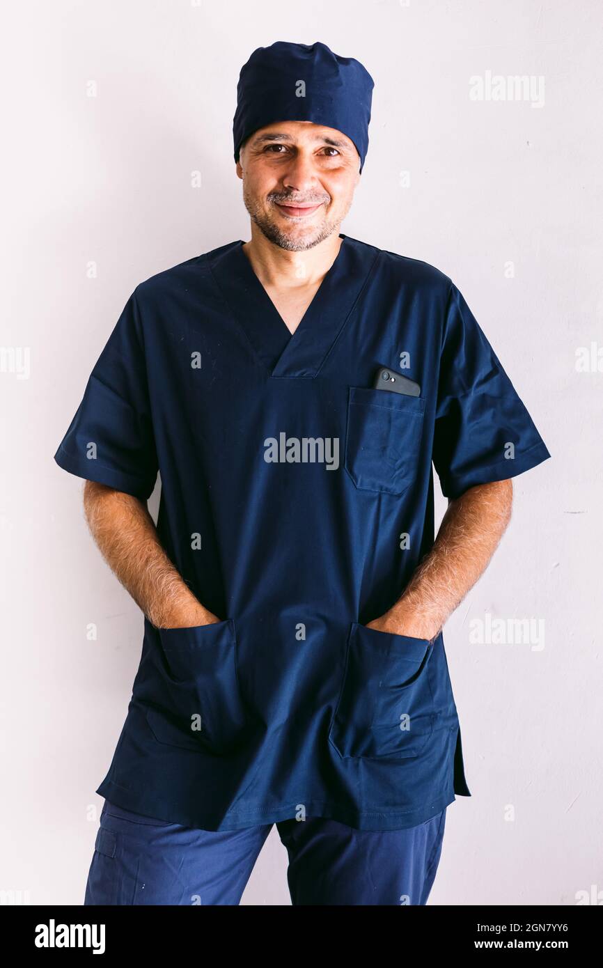Hombre enfermera, médico o veterinario con uniforme azul en una ventana en  un hospital, manos en bolsillos, sonriendo. Concepto de medicina, hospital  y salud Fotografía de stock - Alamy