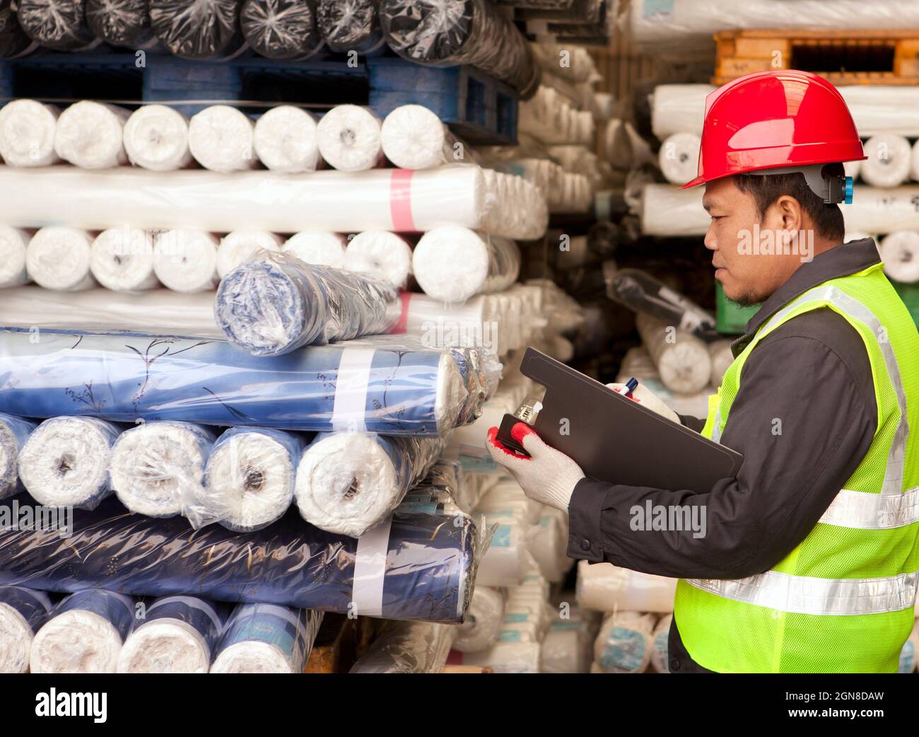 Jefe de la fábrica textil auditando tejidos de materia prima en almacén Foto de stock