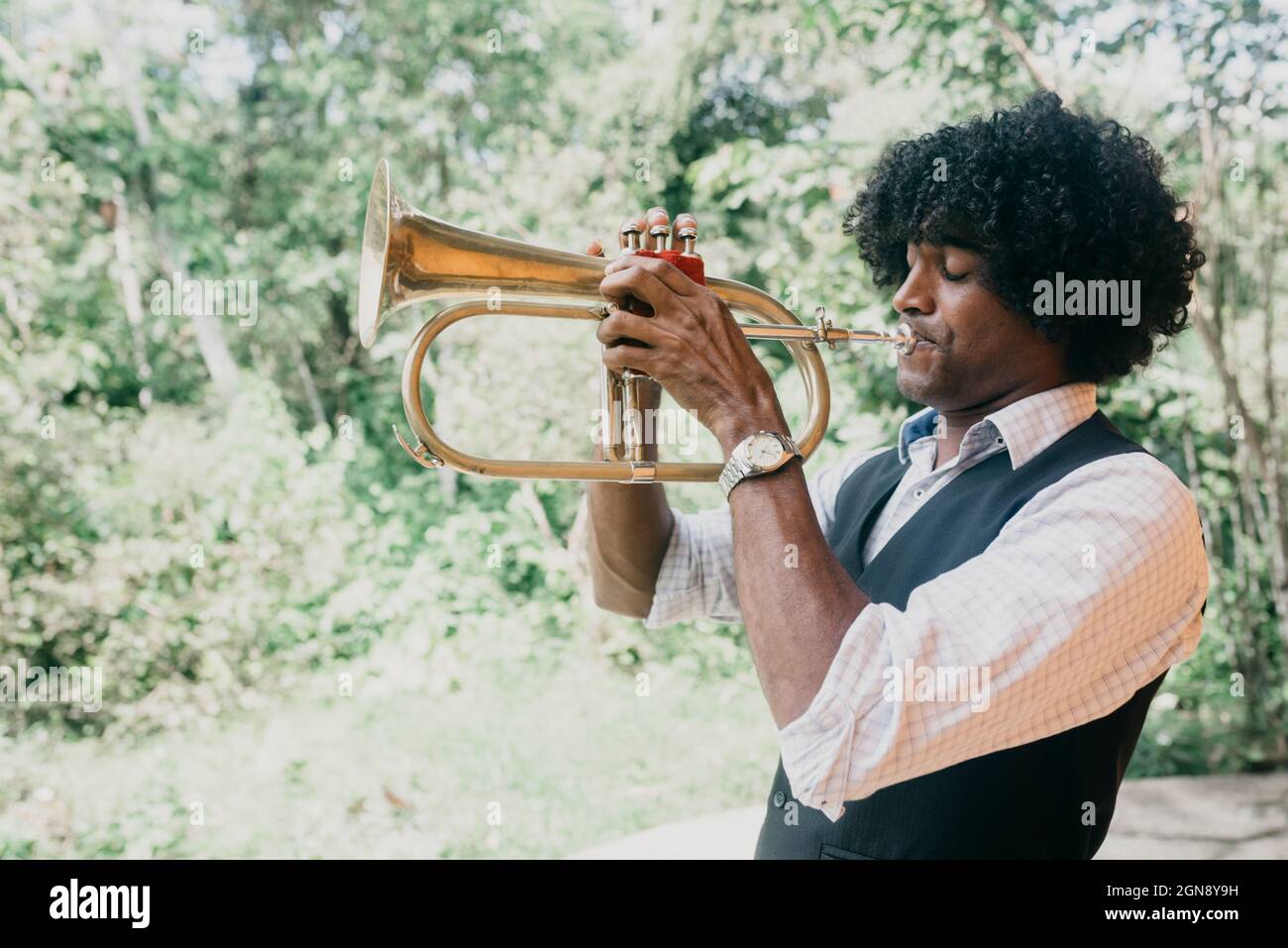 Hombre con cabello rizado negro practicando trompeta Foto de stock