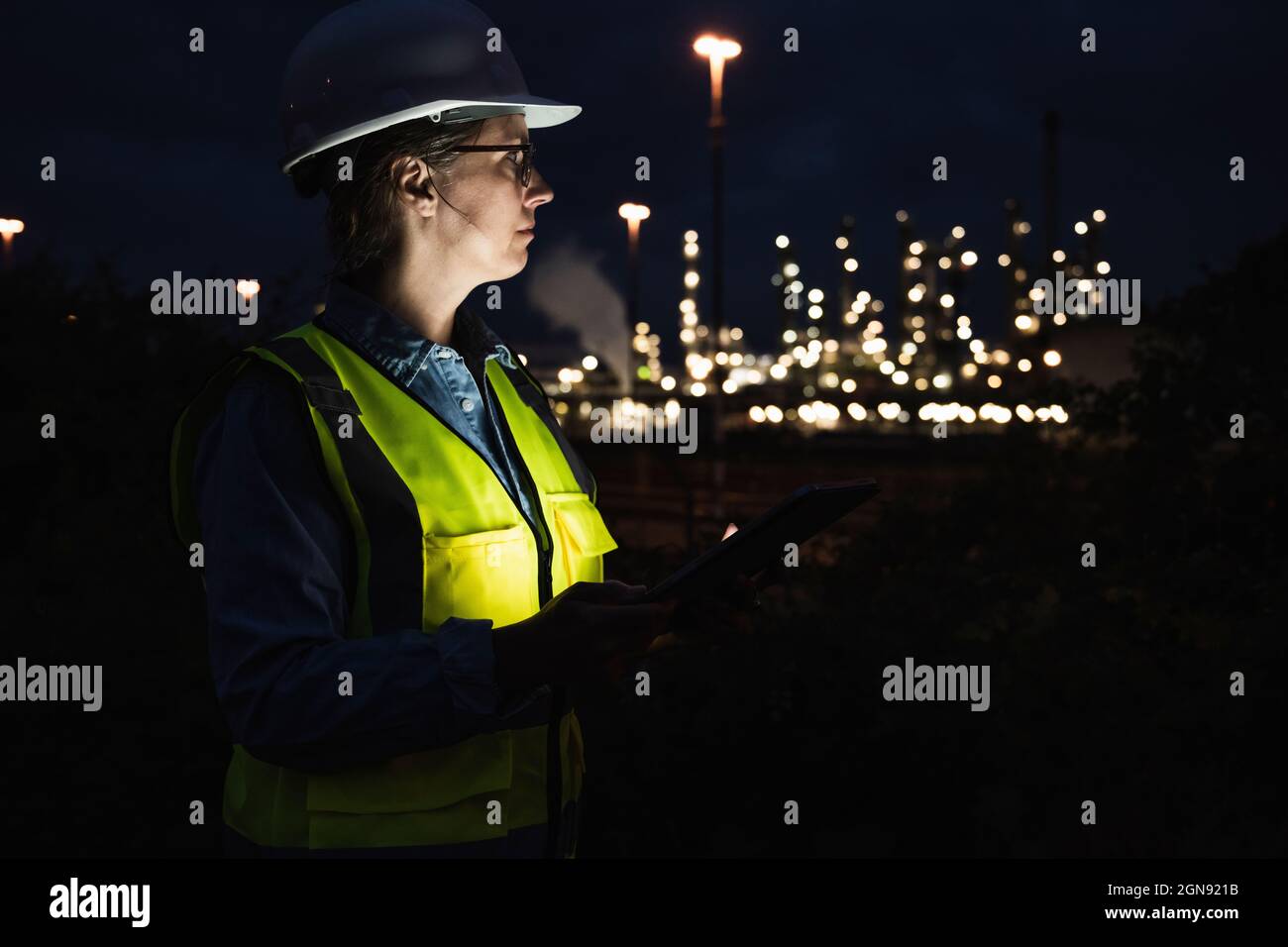 Ingeniero mujer usando casco y ropa reflectante en la fábrica durante la  noche Fotografía de stock - Alamy