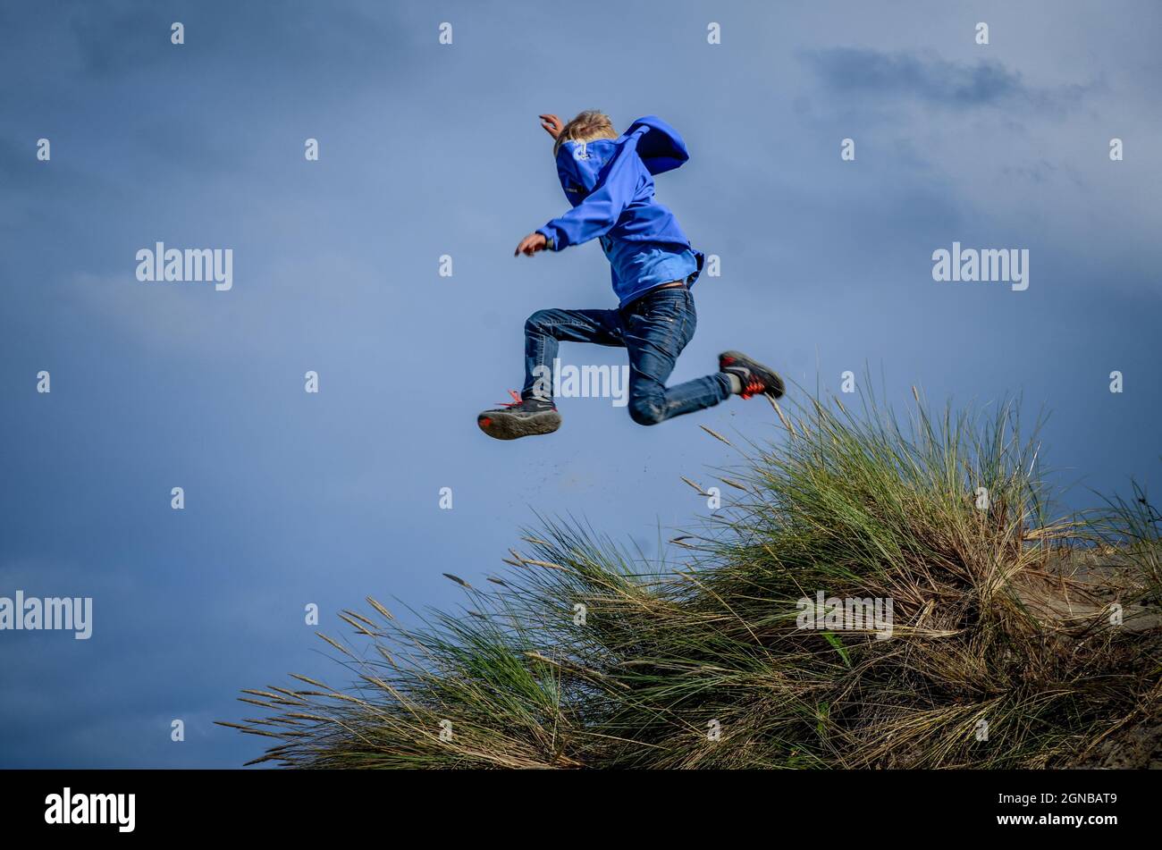 Niño saltando de duna en el aire Foto de stock