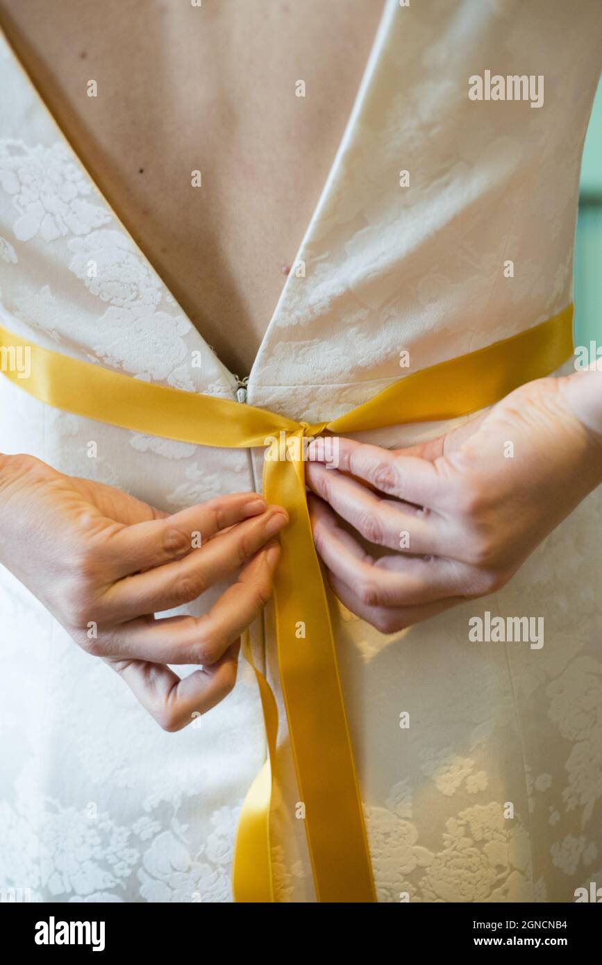 primer plano vertical de la novia atando una cinta amarilla en su vestido  Fotografía de stock - Alamy