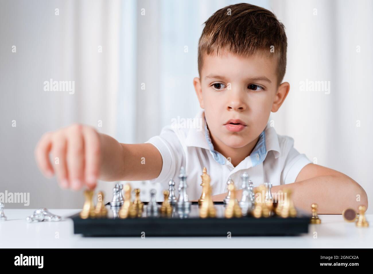 podar Estrecho posición Un niño inteligente aprende a jugar al ajedrez solo en su habitación en  casa Fotografía de stock - Alamy