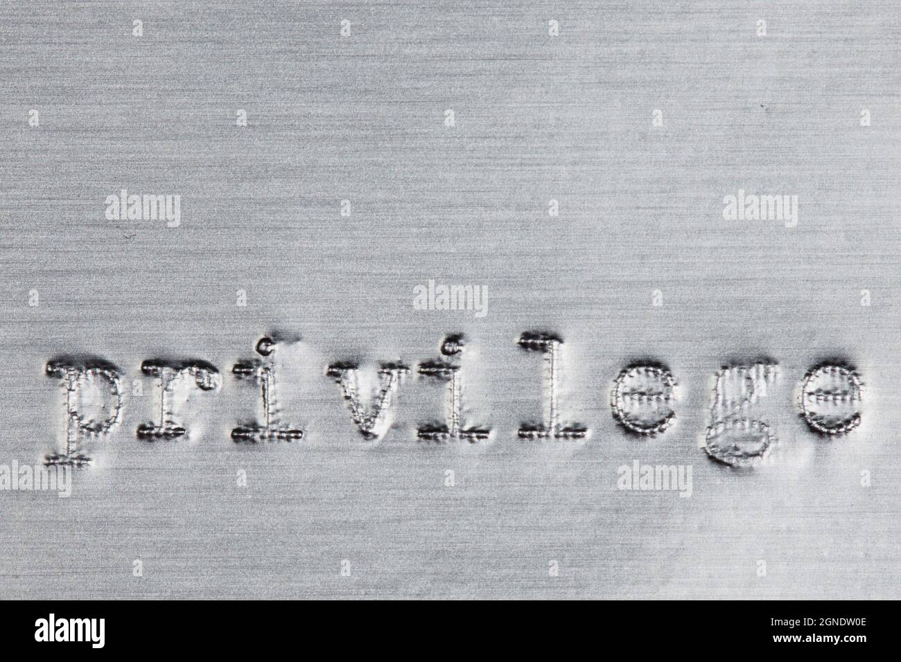 La palabra 'privilegio' impresa en papel de aluminio plateado con una máquina de escribir vintage. Foto de stock