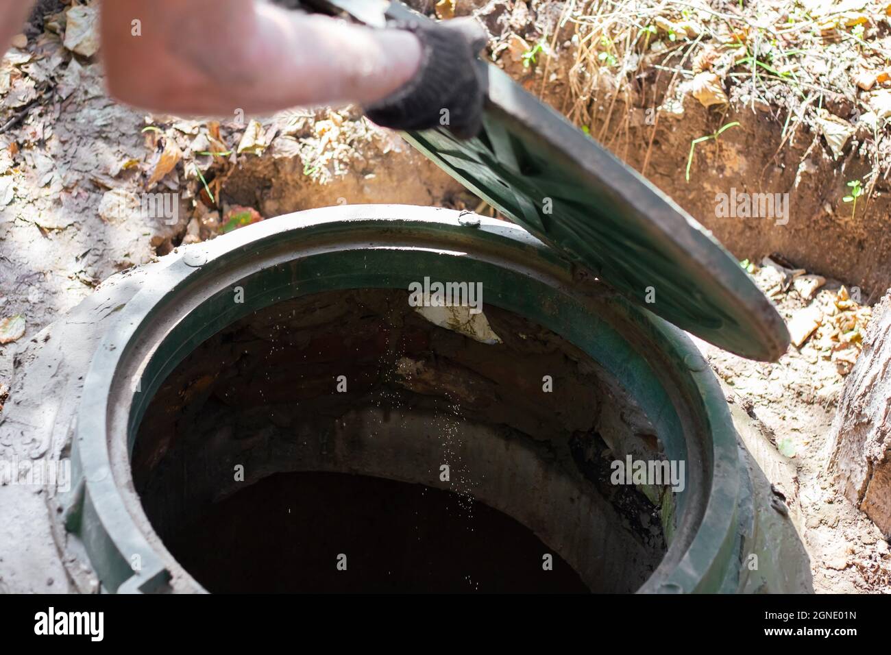 Un trabajador instala una boca de alcantarilla en una fosa séptica