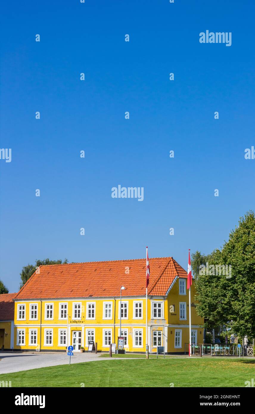 Banderas danesas frente a la colorida casa amarilla en Jelling, Dinamarca Foto de stock