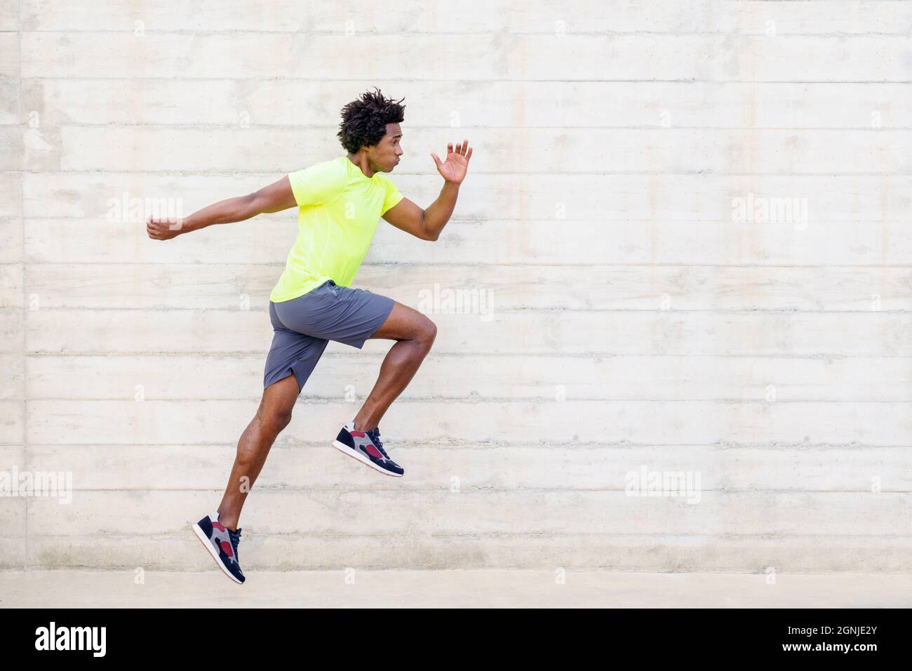 Hombre negro entrenamiento correr saltos para fortalecer sus piernas. Foto de stock