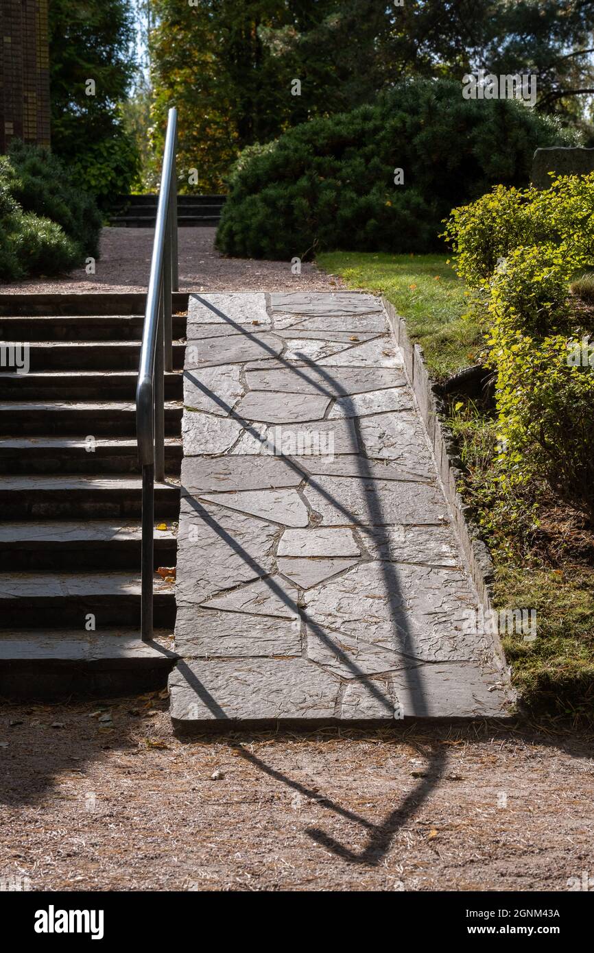 Helsinki / FINLANDIA - 22 DE SEPTIEMBRE de 2021: Barandilla de escalera metálica que proyecta una sombra sobre un pavimento de granito en el cementerio. Foto de stock