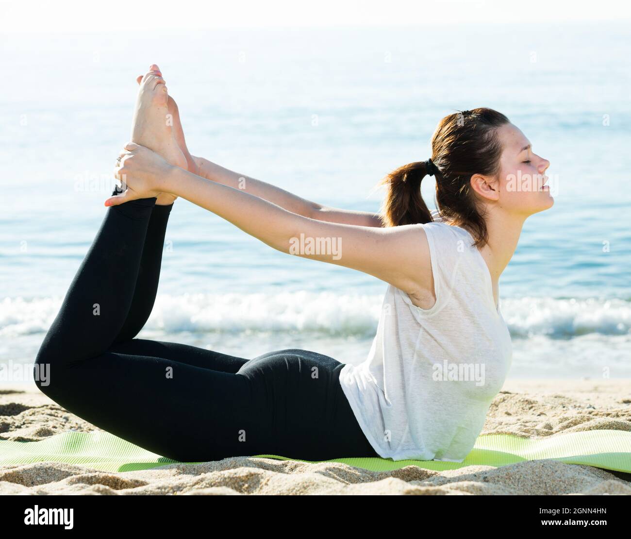 Mujer de 20-30 años practica estiramientos en camiseta blanca Foto de stock