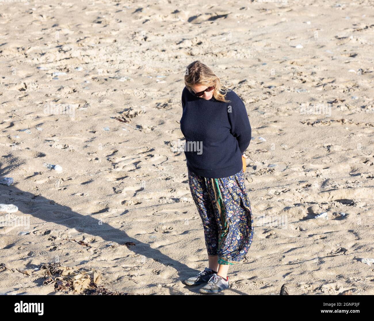 Portreath, Cornwall, 27th de septiembre de 2021, Una señora está mirando bien considerada durante un paseo temprano por la mañana en la playa en marea alta en Portreath, Cornwall. El aparcamiento estaba extrañamente vacío, ya que desde mayo estaba lleno de turistas. El cielo era azul con sol glorioso a pesar de la previsión de tiempo inestable para los próximos días.Crédito: Keith Larby/Alamy Live News Foto de stock