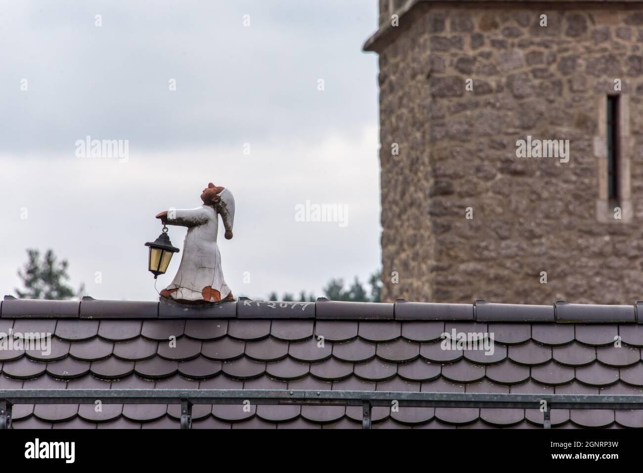 Ein Kunstwerk mit Augenzwinkern: Ein kleiner Schlafwandler auf dem Dachfirst - arte con un guiño del ojo: Un pequeño durmiente a lo largo de la cresta del techo. Foto de stock