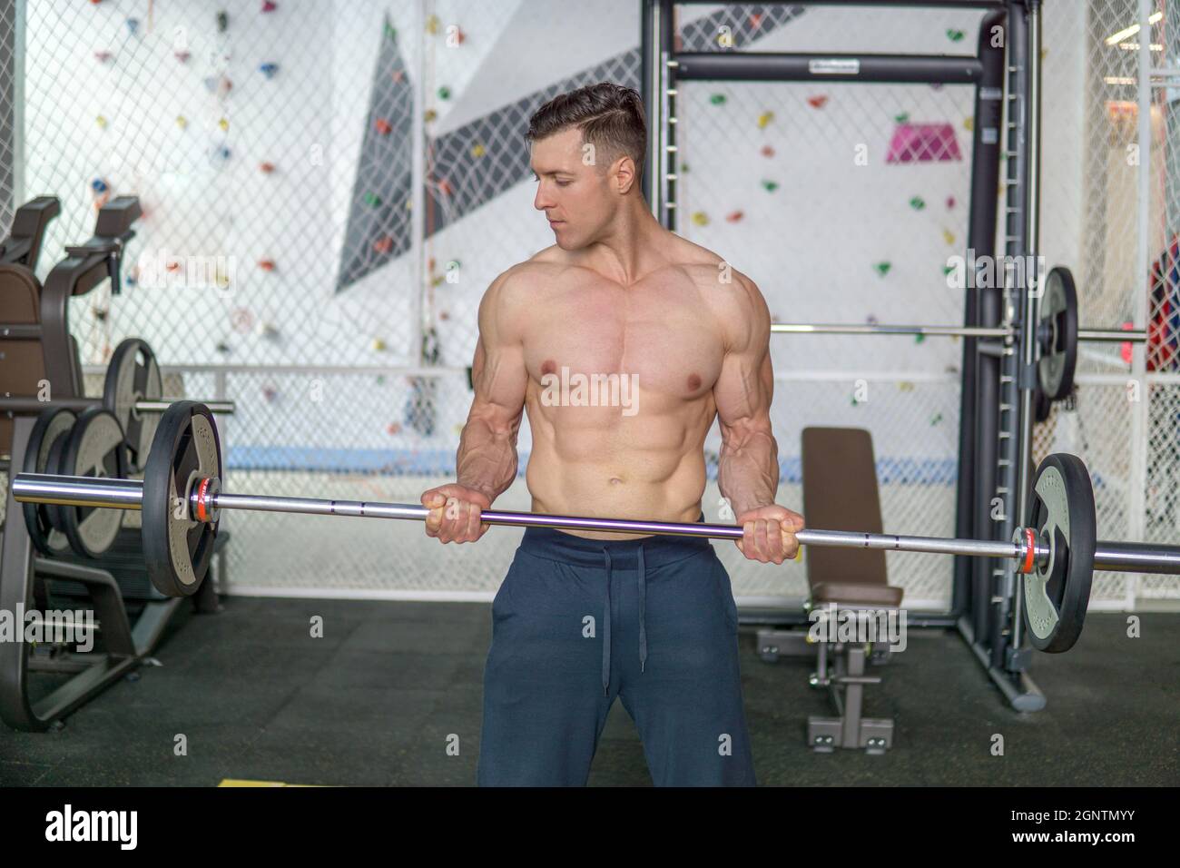 El tipo muscular entrena sus b ceps con una gran barra olimpica