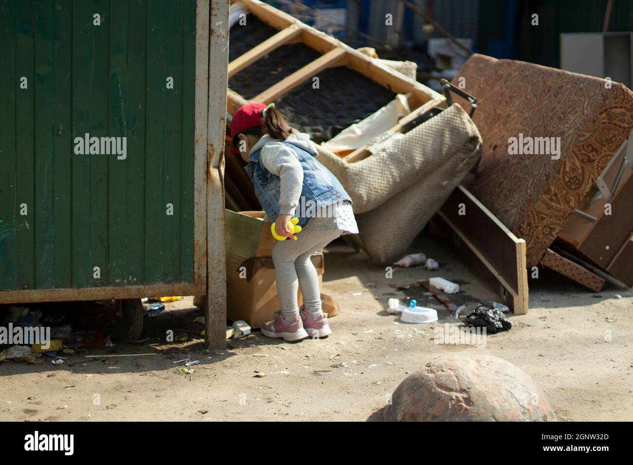 notificación Punto Médico Un niño en un junkyard. La chica está goteando en la basura. El niño  encontró el juguete en el montón de basura. La pobre niña está caminando  sola Fotografía de stock -