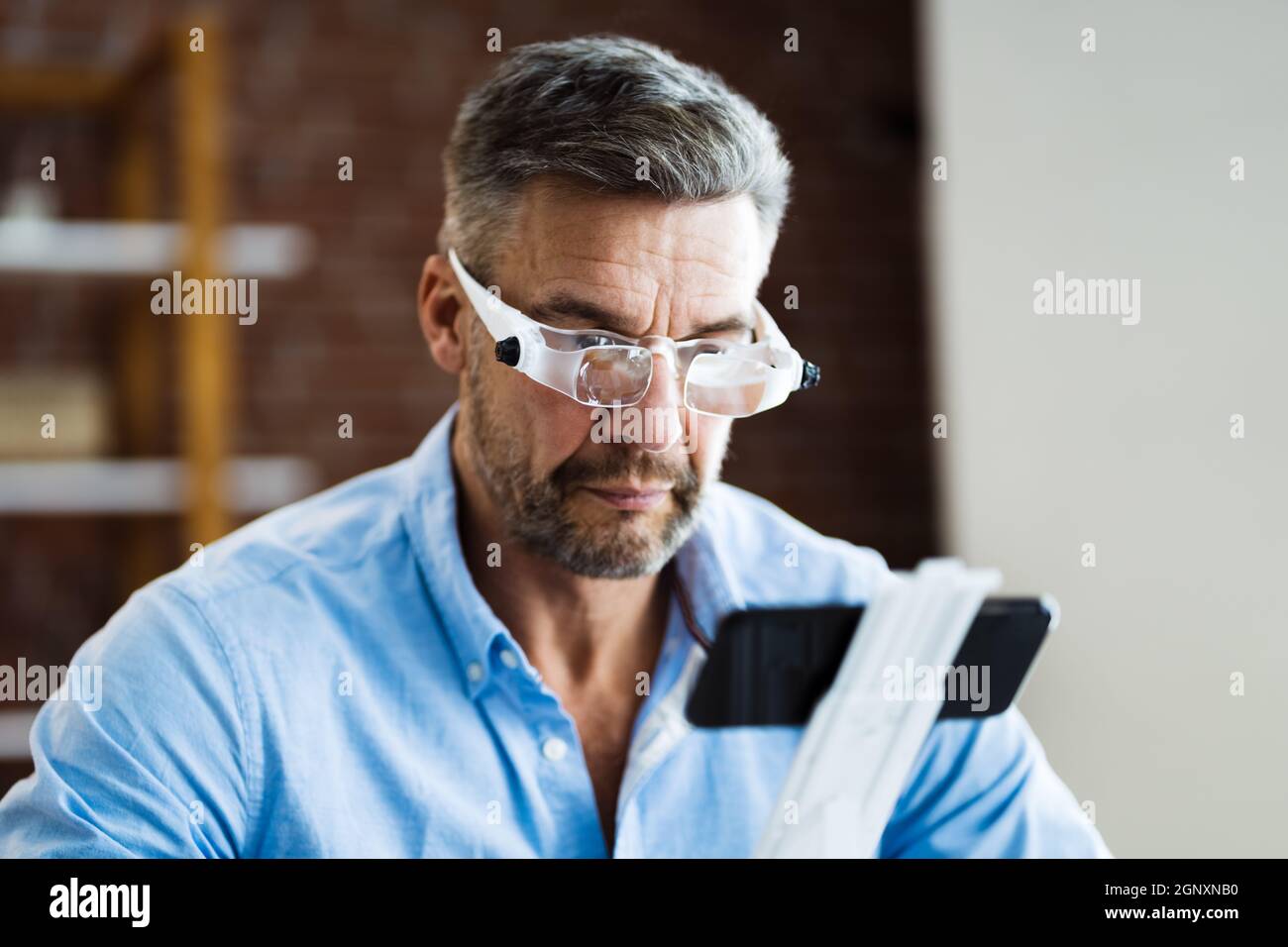 Hombre maduro con gafas de aumento para leer texto en el smartphone  Fotografía de stock - Alamy